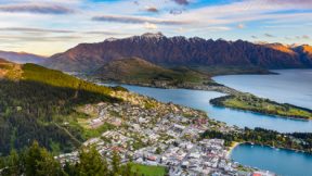Aerial view of Queenstown with a mountain range in the background.